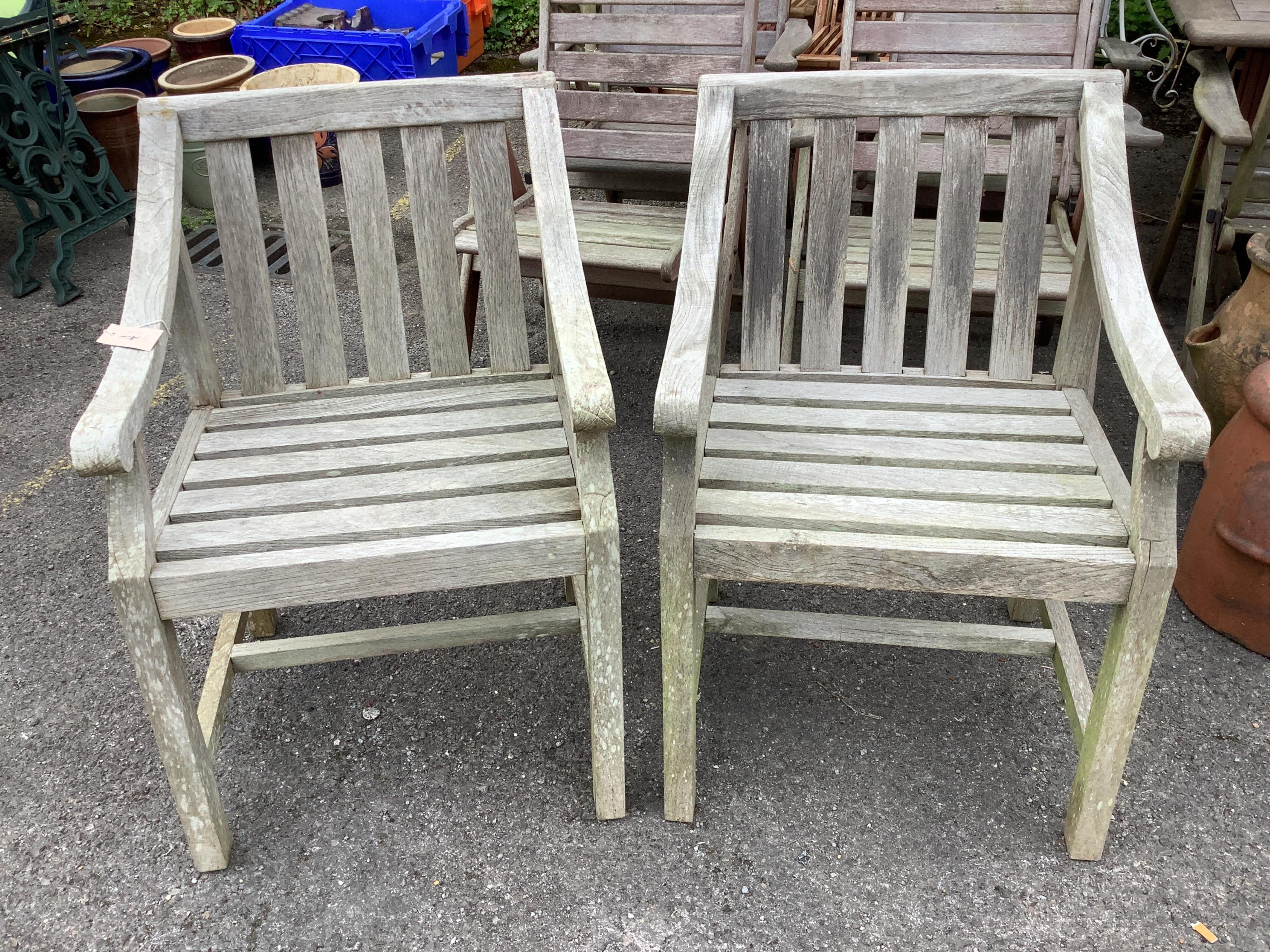 A pair of weathered teak garden elbow chairs, width 57cm, depth 60cm, height 84cm